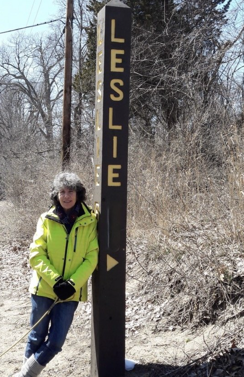 Image of a woman leaning on a poll that says Leslie