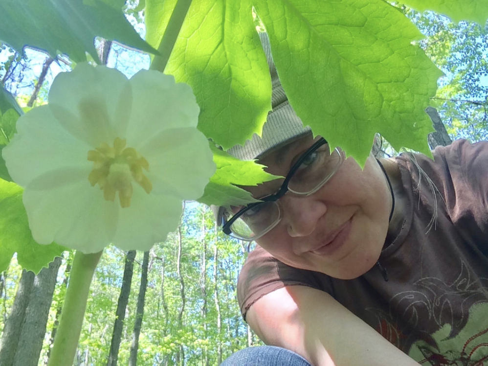 picture of a woman in the forest with a white flower in focus