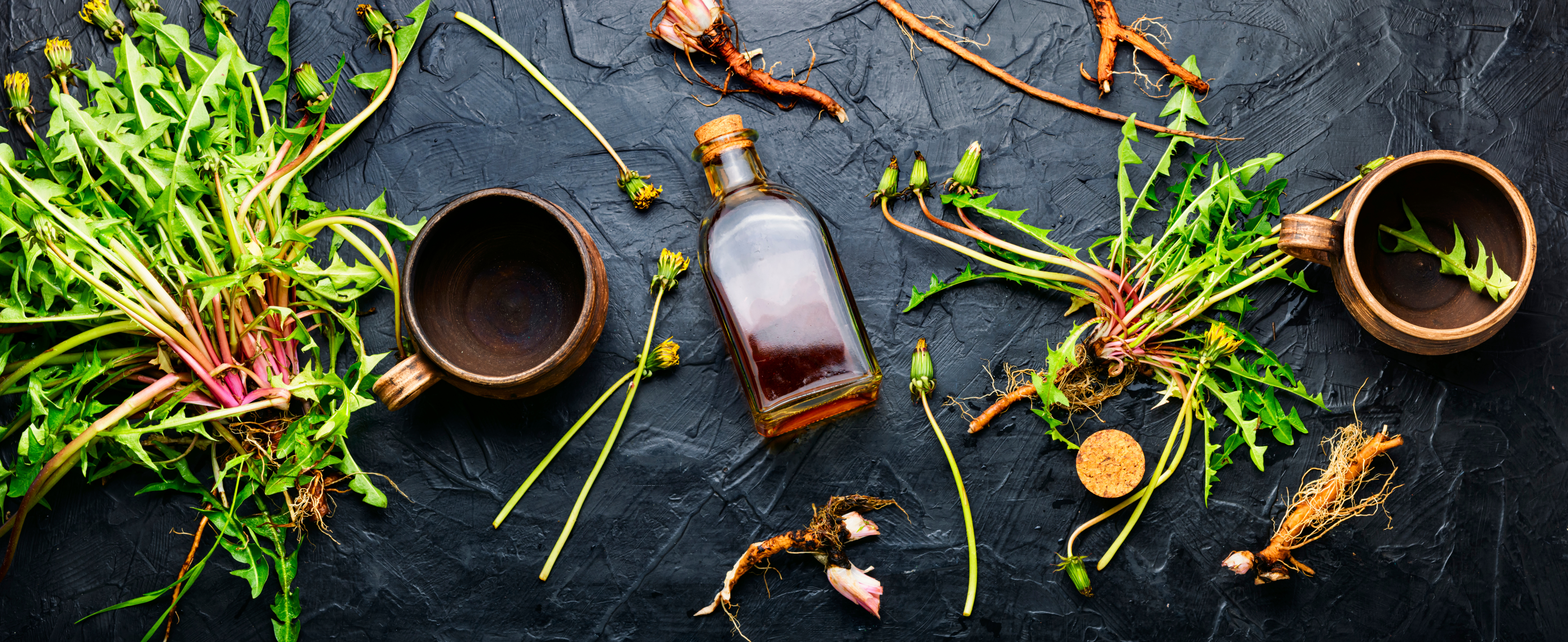 Herbs, bowls, and a glass bottle with oil strewn on a tabletop