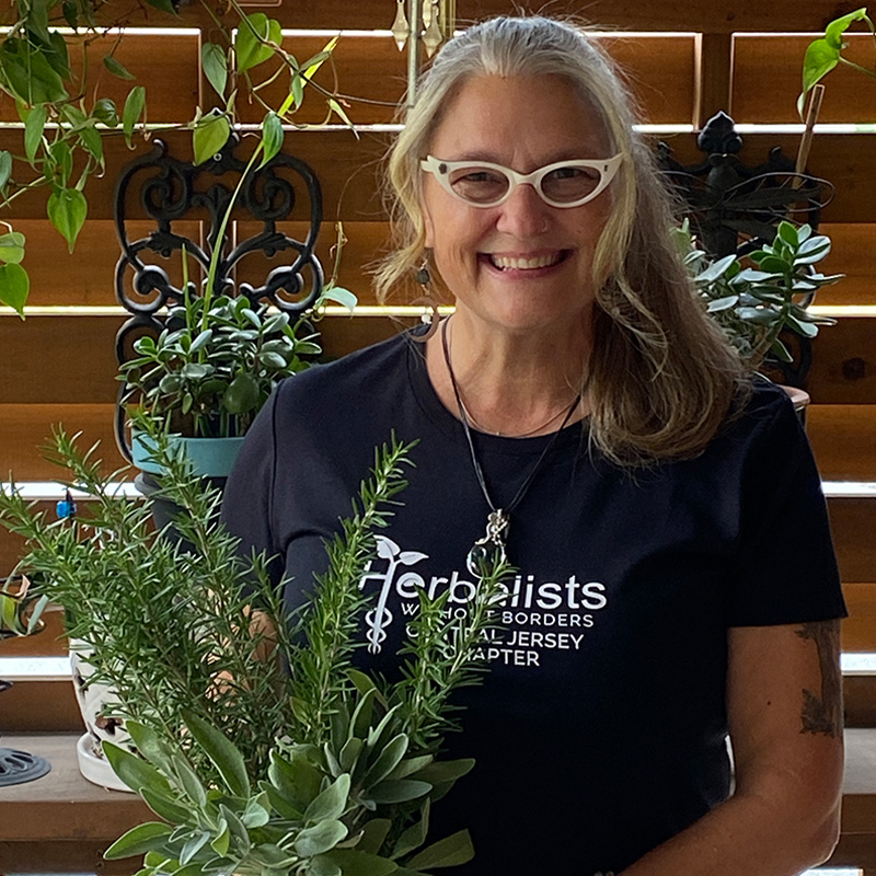 Sheri Kurdakul of HWB Central Jersey Chapter holding herbs on a porch