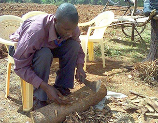 Man whittling at a log of wood